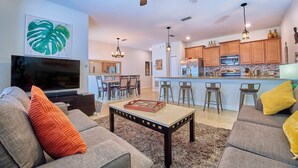 A modern living room with a flat-screen TV, grey sofas, and a coffee table. - Awesome Daydreamer Home, Pool, Waterpark, Slides, Lazy River, near all Parks (Kissimmee)