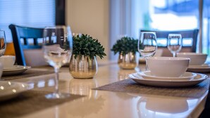 A dining table set with white plates, bowls, and wine glasses, accompanied by small potted plants. - Awesome Daydreamer Home, Pool, Waterpark, Slides, Lazy River, near all Parks (Kissimmee)