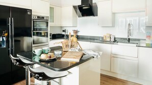 Eine moderne Küche mit schwarzem Kühlschrank, Backofen und Herd, weißen Schränken und einer schwarzen Arbeitsplatte.