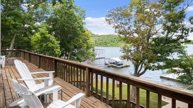 A wooden deck with white Adirondack chairs overlooking a lake with dock and boat. - Group Getaway w/ Dock! Lakefront Escape in Stover (Stover)