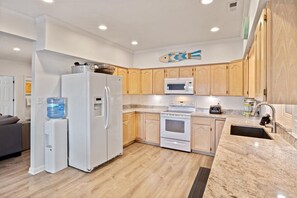 Enjoy cooking in this well-lit kitchen with a refrigerator, microwave, and oven.