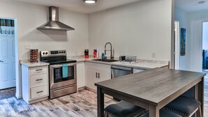 Une cuisine moderne dotée d’appareils électroménagers en acier inoxydable, d’un îlot central et d’un four encastré.