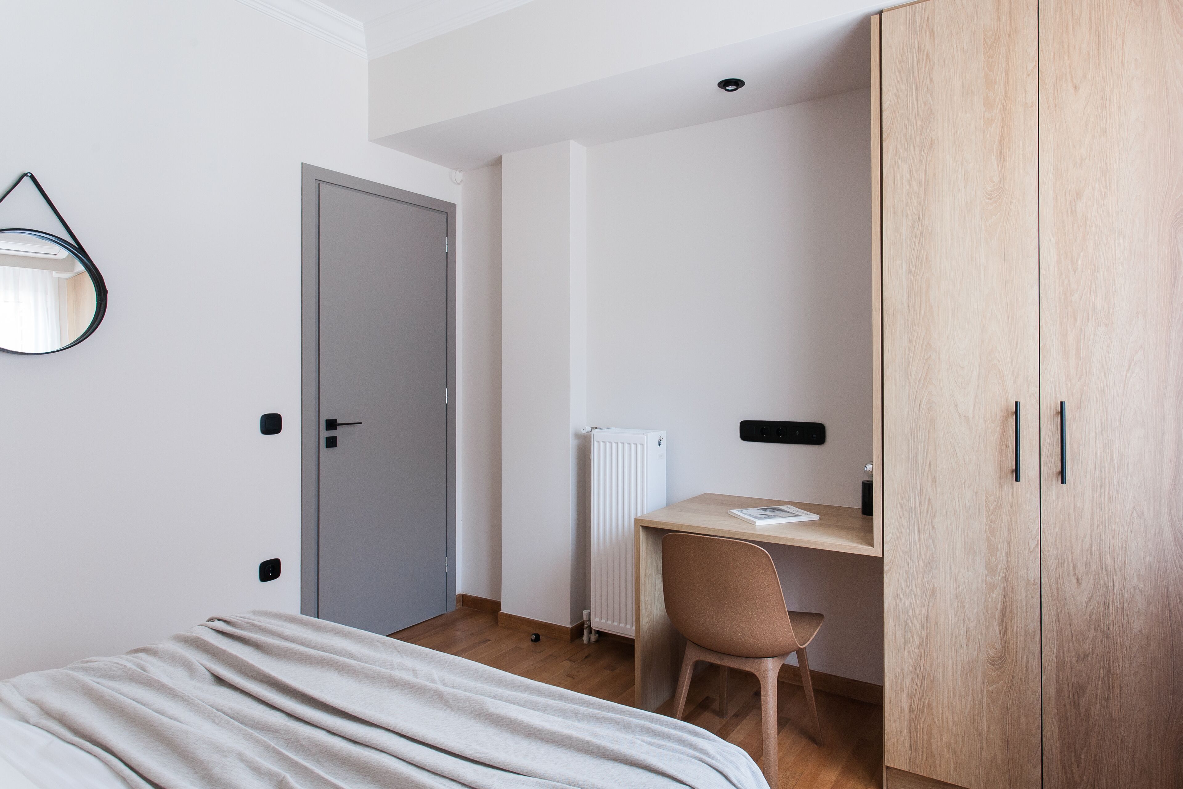 Een slaapkamer met een bed, een bureau met stoel, een kledingkast en een radiator.