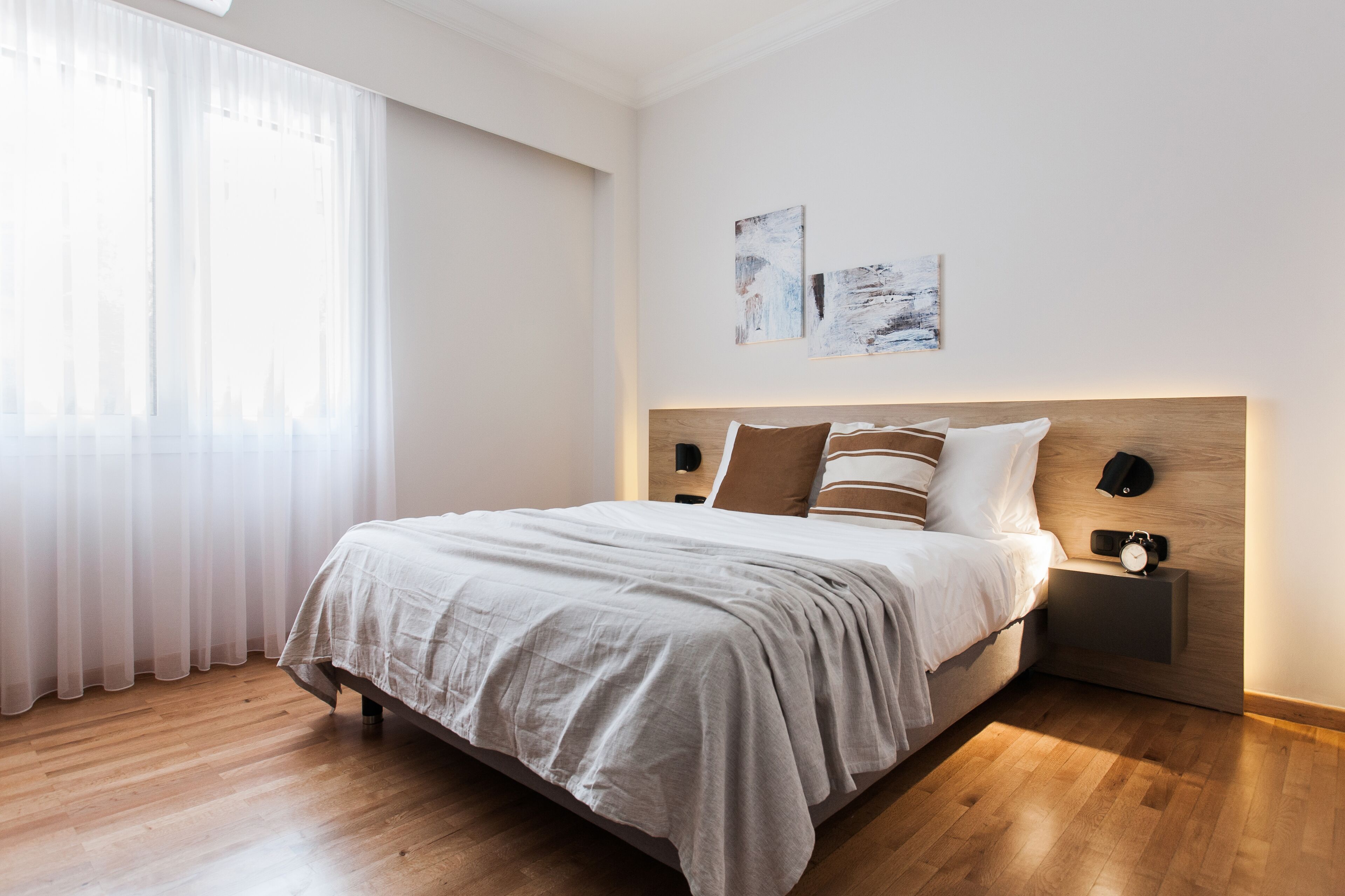 A neatly arranged bedroom with a bed, bedside tables, and artwork on the wall.