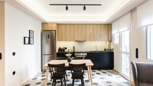 A modern kitchen with a dining area, featuring a hexagonal tile floor, a stainless steel refrigerator, and wooden cabinets. - UPSTREET Modern Minimalist 3BD Apt-Hilton (Athens)