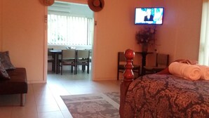 Une chambre d’hôtel équipée d’un lit, d’une télévision, d’un coin repas et offrant une vue sur l’extérieur.