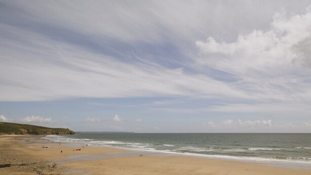 Une plage avec un large rivage sablonneux et des vagues douces.