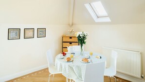 Un coin repas avec une table mise pour le petit-déjeuner, un radiateur et une lucarne.