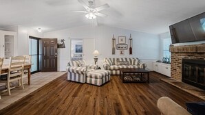 A living room with a fireplace, striped sofas, a coffee table, and a television. - Paradise Cove- Lakefront on a Cove w/Guest Cottage (Kingsland)