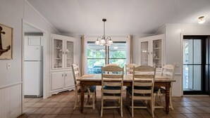 A dining area with a wooden table and chairs, white cabinetry, and a window with a view. - Paradise Cove- Lakefront on a Cove w/Guest Cottage (Kingsland)