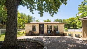 A small stone building with a door, windows, and a porch with seating. - Paradise Cove- Lakefront on a Cove w/Guest Cottage (Kingsland)