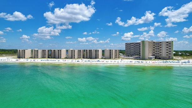 A beachfront hotel with multiple high-rise buildings, a sandy beach, and clear turquoise waters. - Oceanfront PCB Condo w/ Beach Access & 2 Pools (Panama City Beach)