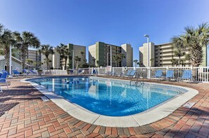 Una piscina con acqua azzurra, circondata da palme e un recinto bianco.