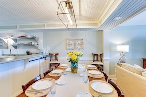 Enjoy meals in this stylish dining area with a long table, decorative wall piece, and comfortable seating.