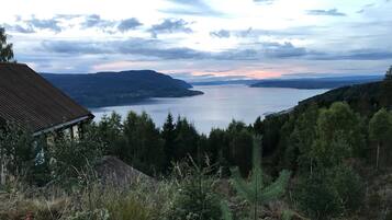 Ein Haus mit Schrägdach mit Blick auf einen See und bewaldete Hügel.