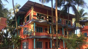 A multi-story building with balconies, surrounded by palm trees. - Nimmu House (Kumta)