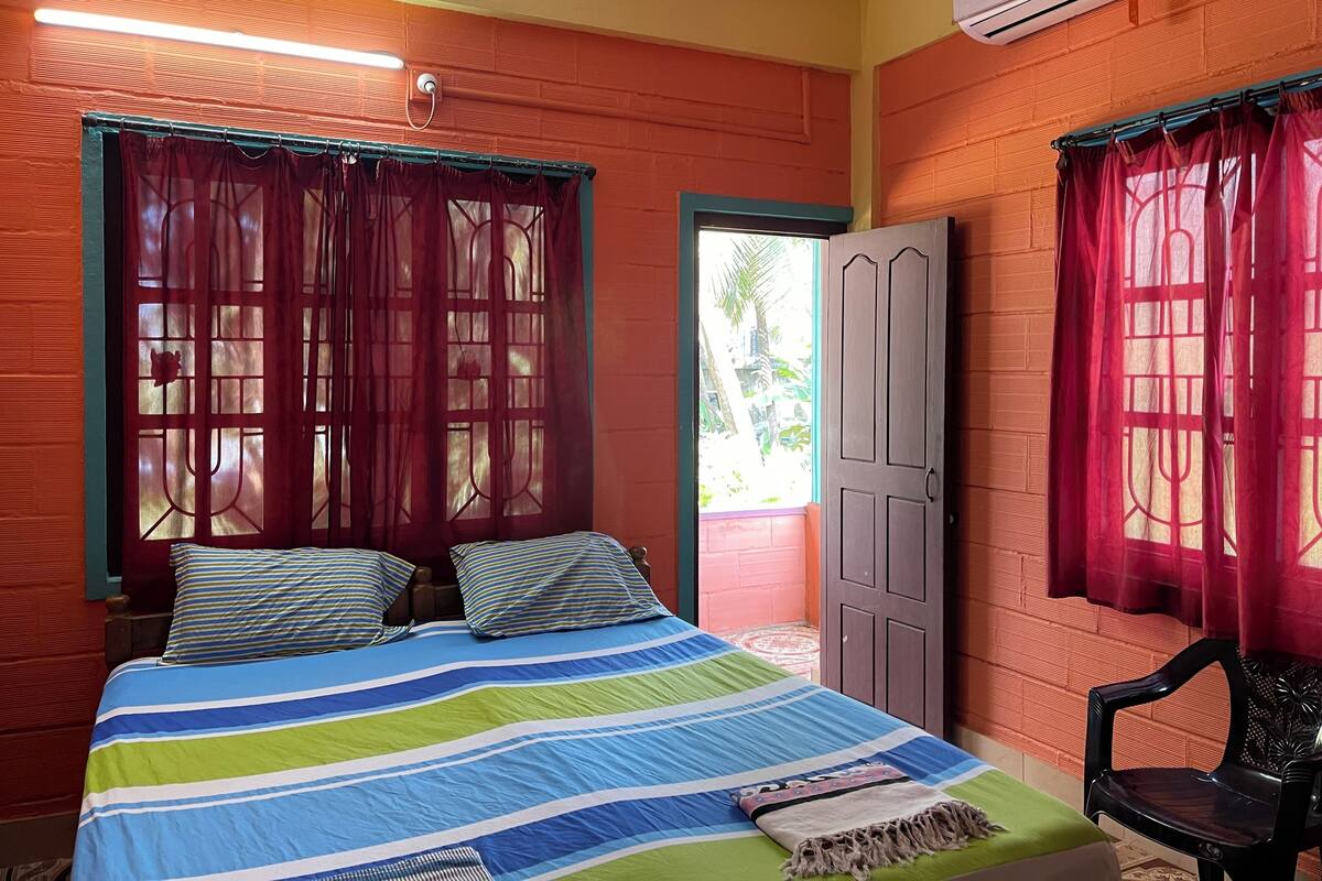 A room with a bed, a chair, and a door.