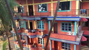 A multi-story building with balconies and windows, surrounded by palm trees. - Nimmu House (Kumta)