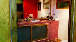 Un baño con lavamanos de baldosas rojas, un espejo y un inodoro.