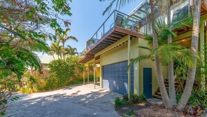 A modern two-story house with a garage, surrounded by lush greenery and palm trees. - Angourie Blue 8 Now Pets considered (Angourie)