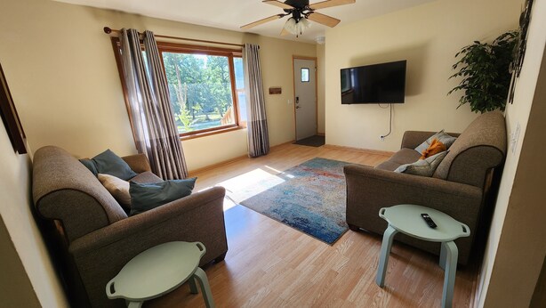 A living room with two sofas, a small table, a TV, and a ceiling fan.