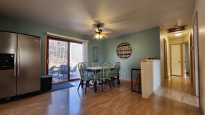 A kitchen with a refrigerator, dining table, chairs, and a ceiling fan.