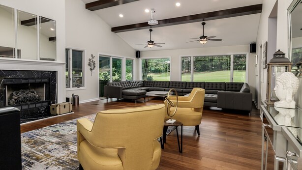 A spacious living room with a fireplace, a large sectional sofa, and a view of a golf course through large windows.