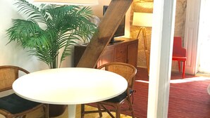 Ett rum med ett runt, vitt bord, två fåtöljer i rotting, en krukväxt och en stor golvlampa.
