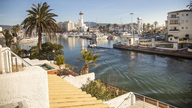 A marina with boats, a lighthouse, and buildings along the waterfront.