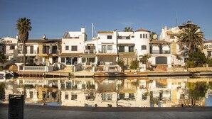 A waterfront property with white buildings, a dock, and a calm reflective pool.