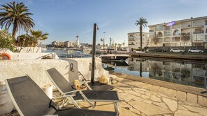 A marina with boats, a lighthouse, and a row of buildings with balconies.
