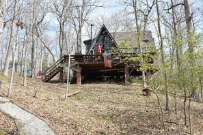 Une cabane dotée d’une terrasse en bois, d’un escalier et d’un petit espace porche.
