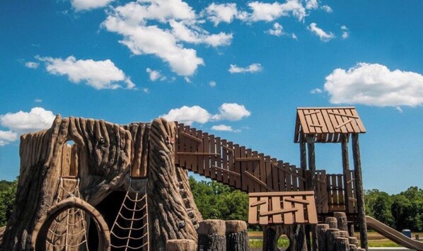 Un parque infantil con estructuras de madera para escalar y un puente colgante.