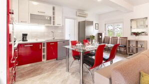 A modern kitchen with red and white cabinets, a dining area with red chairs, and a large window providing natural light.