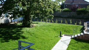 Une cour arrière verdoyante avec un chemin pavé menant à un escalier.