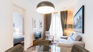 A modern living room with a glass dining table, comfortable seating, a TV, and artwork on the walls. - PUERTA DEL SOL CITY CENTER III WITH BALCONY (Madrid)