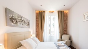 A hotel room with a large bed, a chair, a painting, and a view of the outside. - PUERTA DEL SOL CITY CENTER III WITH BALCONY (Madrid)