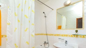 Une salle de bain avec une baignoire, une douche, un lavabo et un miroir.