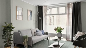 A modern living room with a grey sofa, a coffee table, and a potted plant.