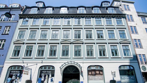 A building with multiple stories, featuring large windows and a central entrance with an archway.