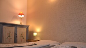 Een hotelkamer met twee bedden, een nachtkastje, een lamp en een muur met bloemenprint.