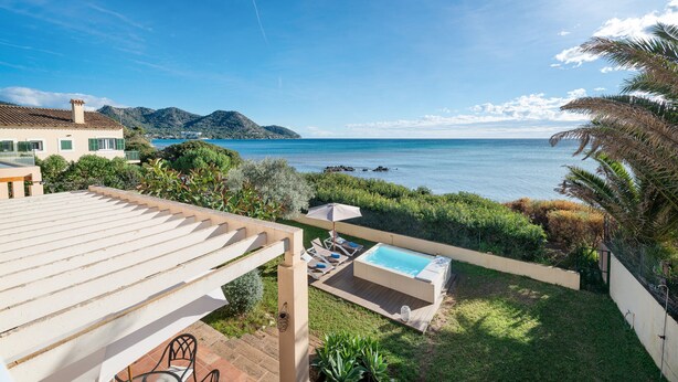 Eine Terrasse mit Whirlpool, Liegestühlen und Meerblick.