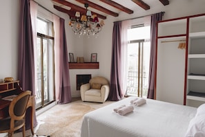 Une chambre à coucher comprenant un lit, une chaise, un bureau, un lustre et une armoire.