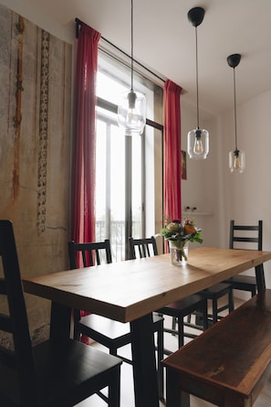 Un coin repas avec une table et des chaises en bois, un vase rempli de fleurs et des lampes suspendues.