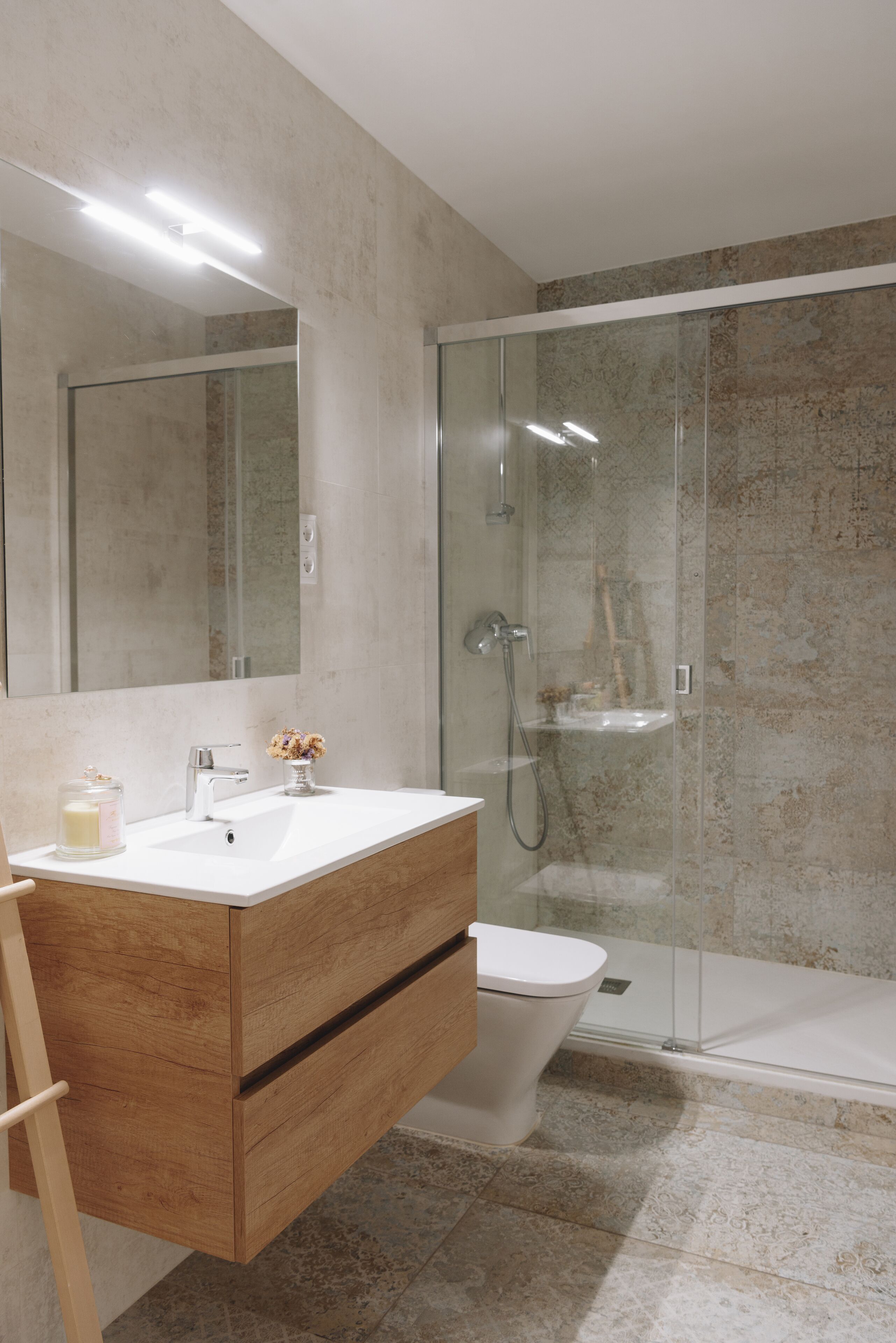 A modern bathroom with a wooden vanity, a glass shower enclosure, and a large mirror.