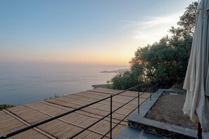 A wooden deck with metal railings overlooking a body of water and a distant landmass.