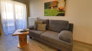 A living room with a grey sofa, a wooden coffee table, and a painting of a cow on the wall. - Gästehaus Wiesegg (Reit im Winkl)