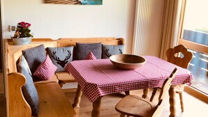 A cozy room with a wooden bench, a table with a checkered tablecloth, and a painting on the wall. - Gästehaus Wiesegg (Reit im Winkl)