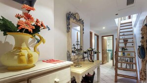A hallway with a yellow vase of flowers, a mirror, a wooden ladder, and a staircase. - Amazing Duplex w/ Stunning Pool by HostWise (Albufeira)