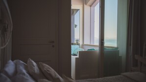 A bedroom with a bed, a sliding glass door leading to a balcony with a view of the sea. - VILLA LILLA penthouse on the beach of San Vincenzo Tuscany luxury (San Vincenzo)